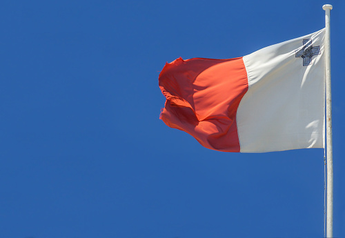 The national flag of Malta blows in the wind on a flagpole