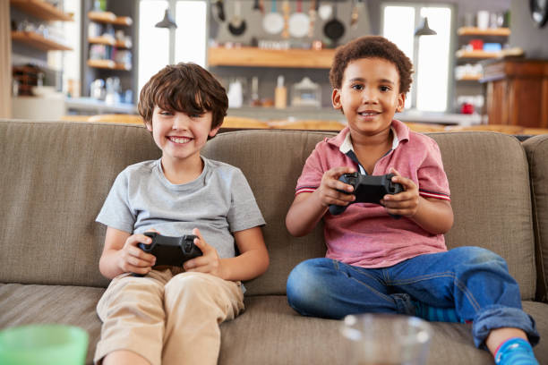 istock Two Boys Sitting On Sofa In Lounge Playing Video Game Together 807397320