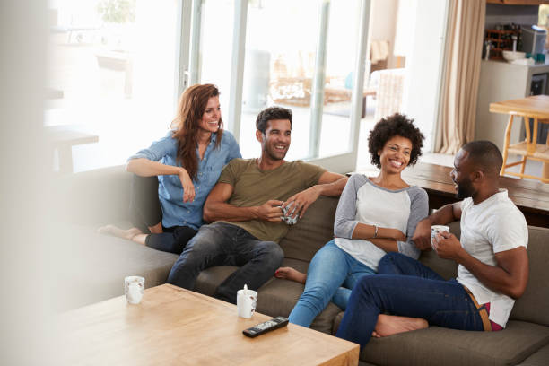istock Couple Sitting On Sofa With Friends At Home Talking 807397328