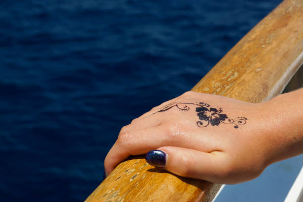 A female hand holds the handrail of a boat A photograph of a female hand holding onto the handrail of a boat in the Mediterranean sea, Malta. There is a floral design henna tattoo on the back of the hand. wrist tattoo stock pictures, royalty-free photos & images