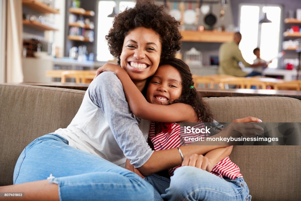 Portrait Of Mother And Daughter Sitting On Sofa Laughing Mother Stock Photo