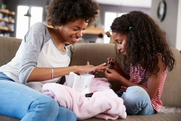 Photo of Daughter Sitting On Sofa At Home Painting Mother's Nails