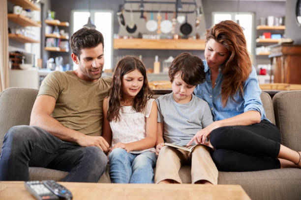 istock Family Sitting On Sofa In Lounge Reading Book Together 807401992
