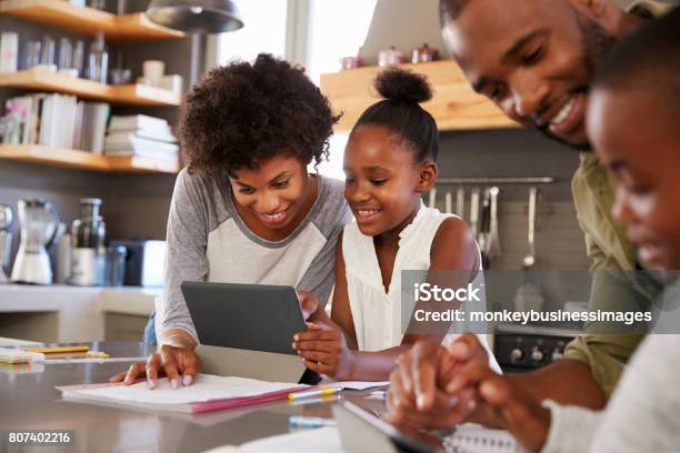 Parents Helping Children With Homework In Kitchen Stock Photo - Download Image Now - Homework, Family, Child