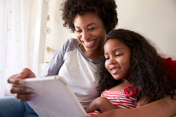 istock Mother And Daughter Siting On Bed Using Digital Tablet 807405422
