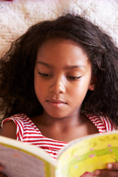 istock Overhead View Of Girl Lying On Bed And Reading Book 807406074