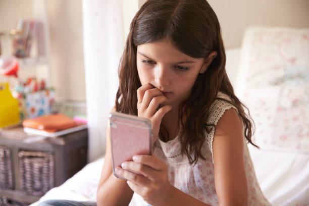 Young Girl In Bedroom Worried By Bullying Text Message Young Girl In Bedroom Worried By Bullying Text Message teasing photos stock pictures, royalty-free photos & images
