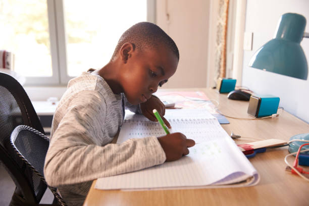 istock Young Boy In Bedroom Sitting At Desk Doing Homework 807406496