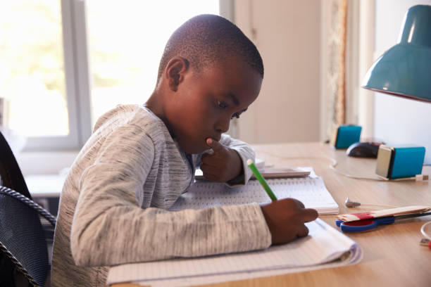 istock Young Boy In Bedroom Sitting At Desk Doing Homework 807408350