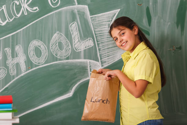 istock Young school girl holding a lunch bag 807408768