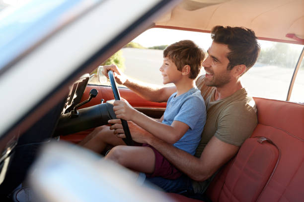 istock Father Teaching Young Son To Drive Car On Road Trip 807410020