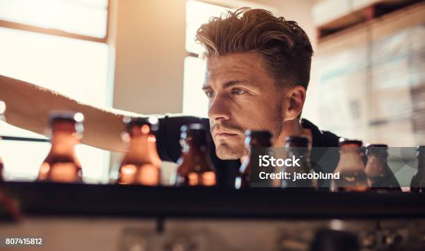 Man Examining The Beer Bottles On Conveyor At Brewery Factory Stock Photo - Download Image Now