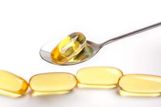 istock Close up a soft gel capsules on spoon with blurred another capsules in background, essential oil supplement intake concept. 807415908