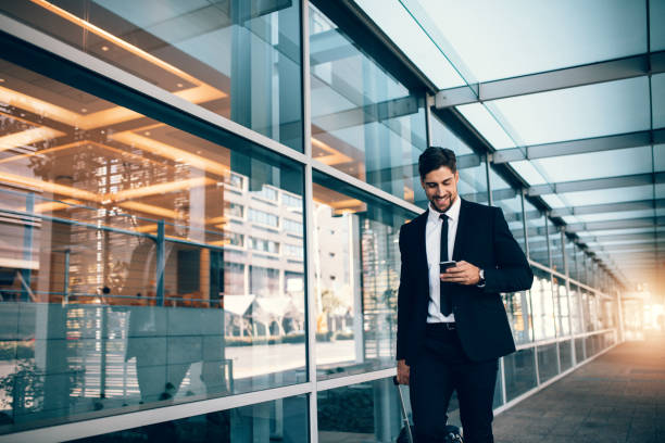 young businessman walking with mobile phone at airport - business travel people traveling airport journey imagens e fotografias de stock