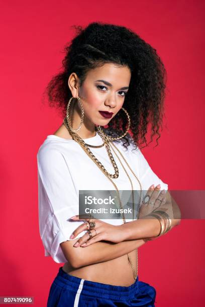 Confident Latin Young Woman In Hiphop Style Against Red Background Stock Photo - Download Image Now