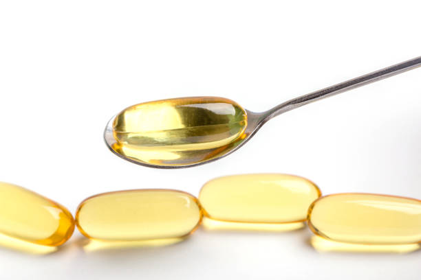 istock Close up a soft gel capsules on spoon with blurred another capsules in background, essential oil supplement intake concept. 807420298