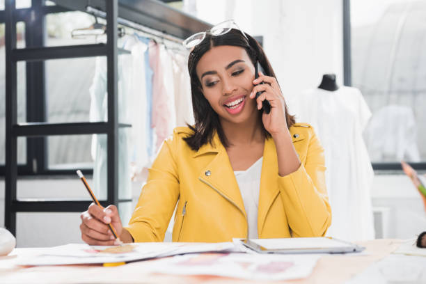 istock smiling woman talking on smartphone during work in clothing design studio 807425086