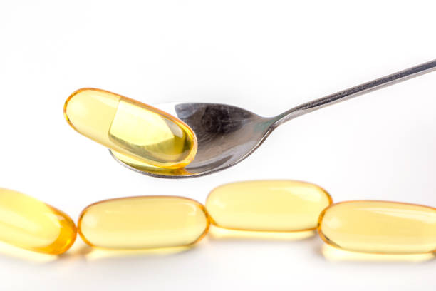 istock Close up a soft gel capsules on spoon with blurred another capsules in background, essential oil supplement intake concept. 807428722