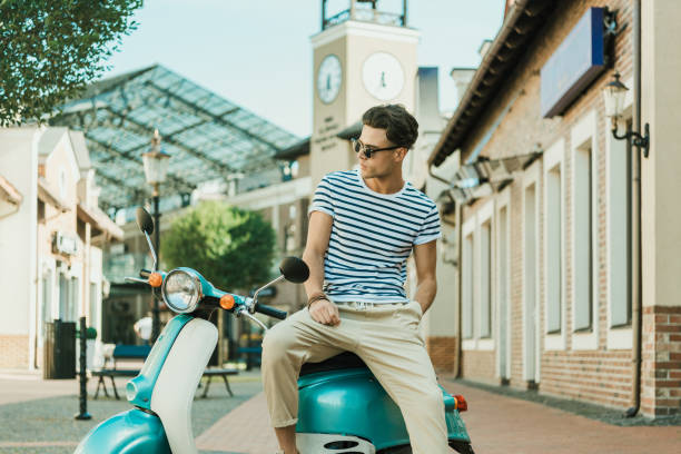 istock man sitting on retro scooter parked on street and looking away 807430470