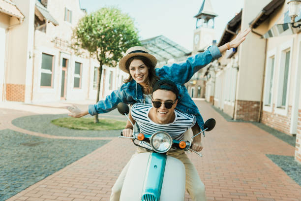 istock Happy stylish young couple riding scooter  and smiling at camera 807433238