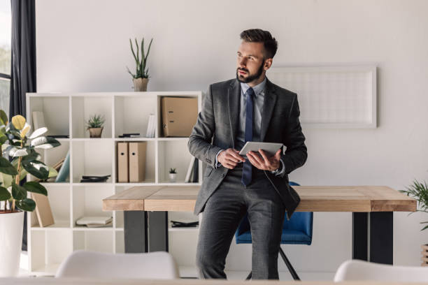 istock young bearded pensive businessman using digital tablet in modern office 807434318