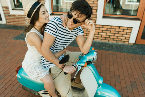 istock Happy stylish young couple riding scooter  together 807434406