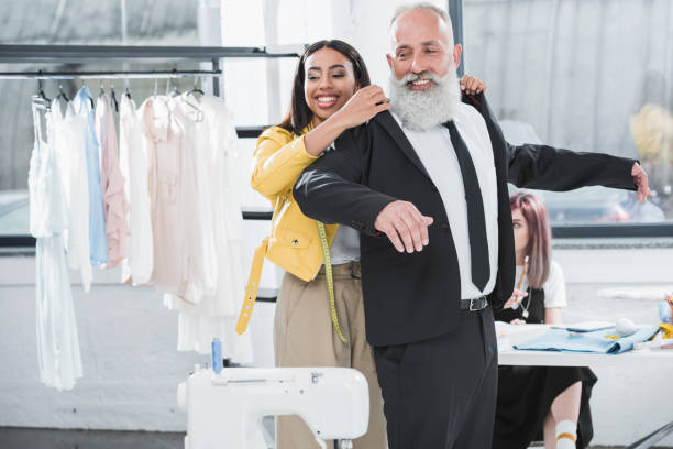 uomo anziano sorridente con giovane afro-americano stilista giacca abito in casa - mannequin dressmakers model tape measure female foto e immagini stock