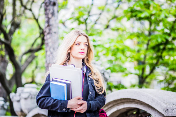 istock Beautiful female student walking outdoors with books 807451290