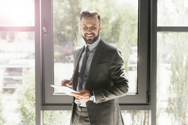 istock smiling businessman in suit using digital tablet at modern office 807465410