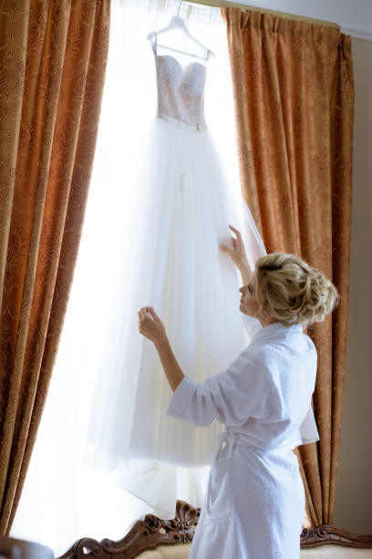 istock Beautiful bride in robe is watching a wedding dress 807485756