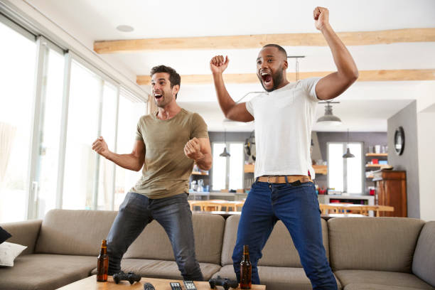 Two Excited Male Friends Celebrate Watching Sports On Television Two Excited Male Friends Celebrate Watching Sports On Television cheering photos stock pictures, royalty-free photos & images