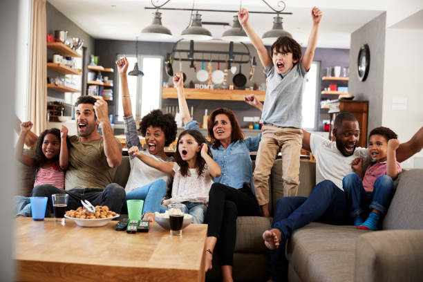 dos familias mirando deportes en la televisión y animando - family television watching watching tv fotografías e imágenes de stock