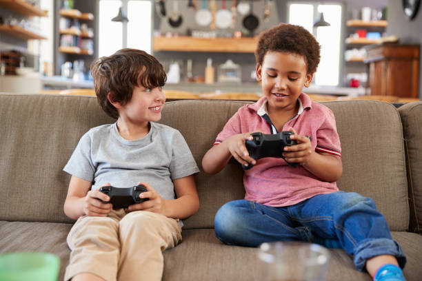 istock Two Boys Sitting On Sofa In Lounge Playing Video Game Together 807487440