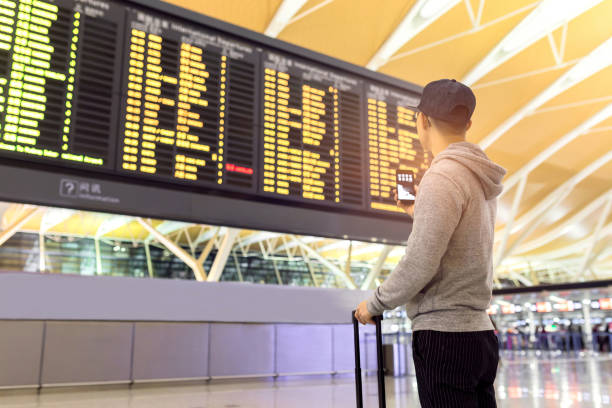 istock Passenger looking at flights information board in airport terminal 807509554