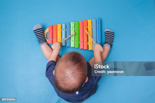 Bird Eye View Of Cute Little Asian 18 Months 1 Year Old Baby Boy Child Hold Sticks Plays A Musical Instrument Colorful Wooden Toy Xylophone Stock Photo - Download Image Now