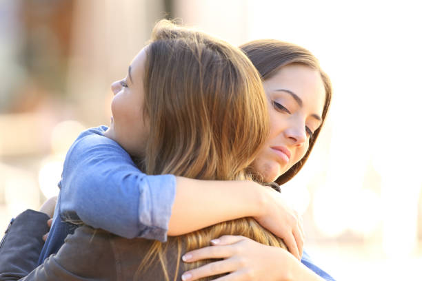 Hypocritical girl embracing a friend stock photo