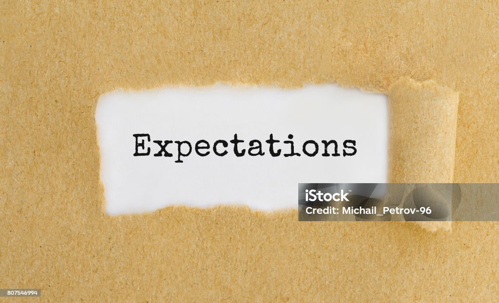 Text Expectations appearing behind ripped brown paper. Anticipation Stock Photo