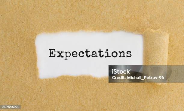 Text Expectations Appearing Behind Ripped Brown Paper Stock Photo - Download Image Now