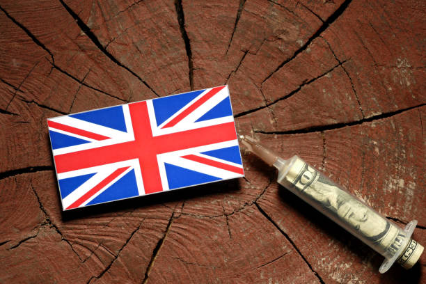 bandiera del regno unito su un ceppo con siringa che inietta denaro in bandiera - british flag currency banking uk foto e immagini stock