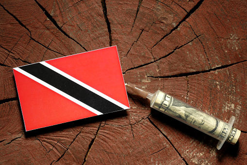Trinidad and Tobago flag on a stump with syringe injecting money in flag