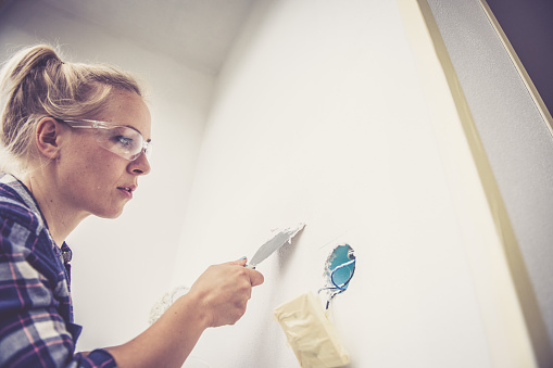 Portrait of caucasian blonde woman with protective eyeglasses. Home renovation, painting. Slovenia, Europe. No logos. Nikon, indoor photography.