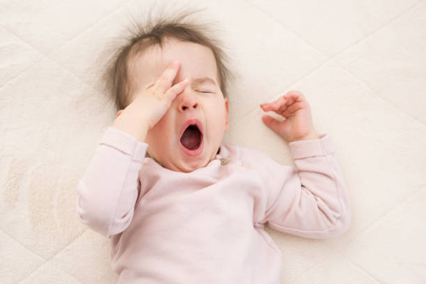 Portrait of sleeping beautiful and yawning baby toddler on the bed wearing pink pullover. Bedtime. Nursery beautiful toddler, baby sleeping on the bed yawning girl stock pictures, royalty-free photos & images