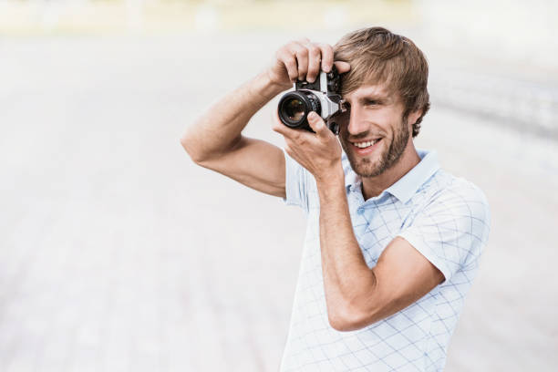 istock Young man with photo camera is taking pictures 807688480