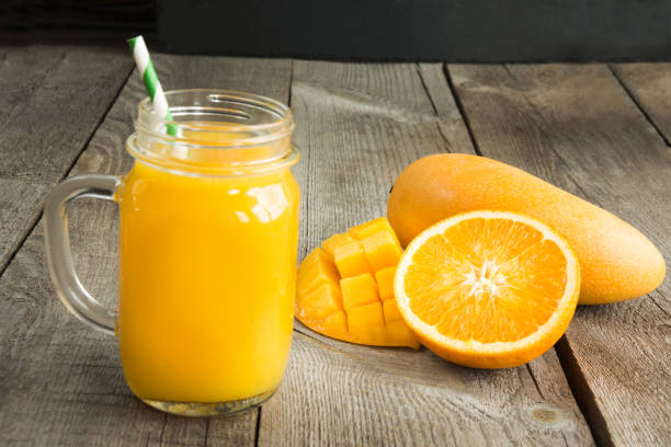 mango and orange juice and slice of orange on wooden table. fresh healthy tropical drink. - orange smoothie imagens e fotografias de stock