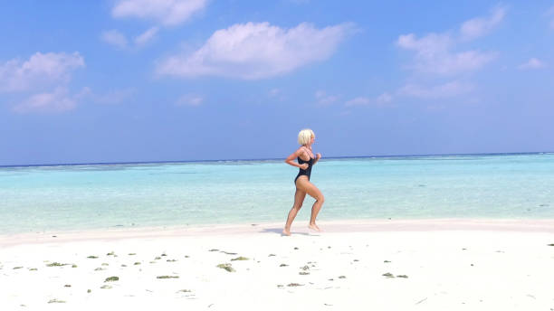 mujer en bikini corriendo por el agua en playa, maldivas - blond hair overcast sun sky fotografías e imágenes de stock