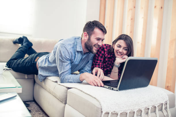 istock Smiling Couple Lying on Sofa and Using Laptop at Home 807765250