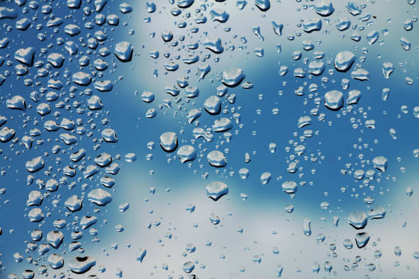 istock Rain drops on window glass with blue cloudy sky in background , spring rainy day 807775834