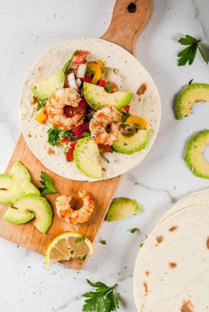 Tacos with salsa and shrimp Seafood. Mexican food. Tortilla tacos with traditional homemade salsa salad, parsley, fresh lemon, avocado and grilled shrimp pawns. On a white marble background. Top view copy space fresh cilantro stock pictures, royalty-free photos & images