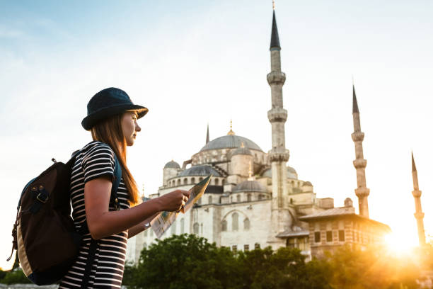 istock A young beautiful traveler girl in a hat with a backpack is watching a map next to the blue mosque - the famous sight of Istanbul. Travel, tourism, sightseeing. 807799574