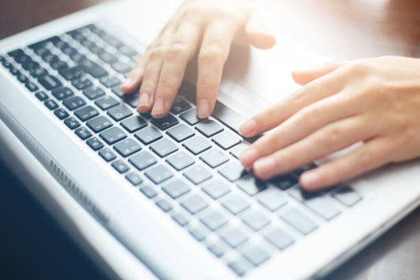 istock Cropped close up shot of woman's hands typing on keyboard while chatting using computer laptop sitting at wooden table. Human, leisure and modern technology concept. Film effect. 807827874